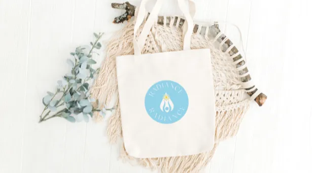 Tote bag with "RADIANCE" logo on macramé and eucalyptus leaves, on a white background.