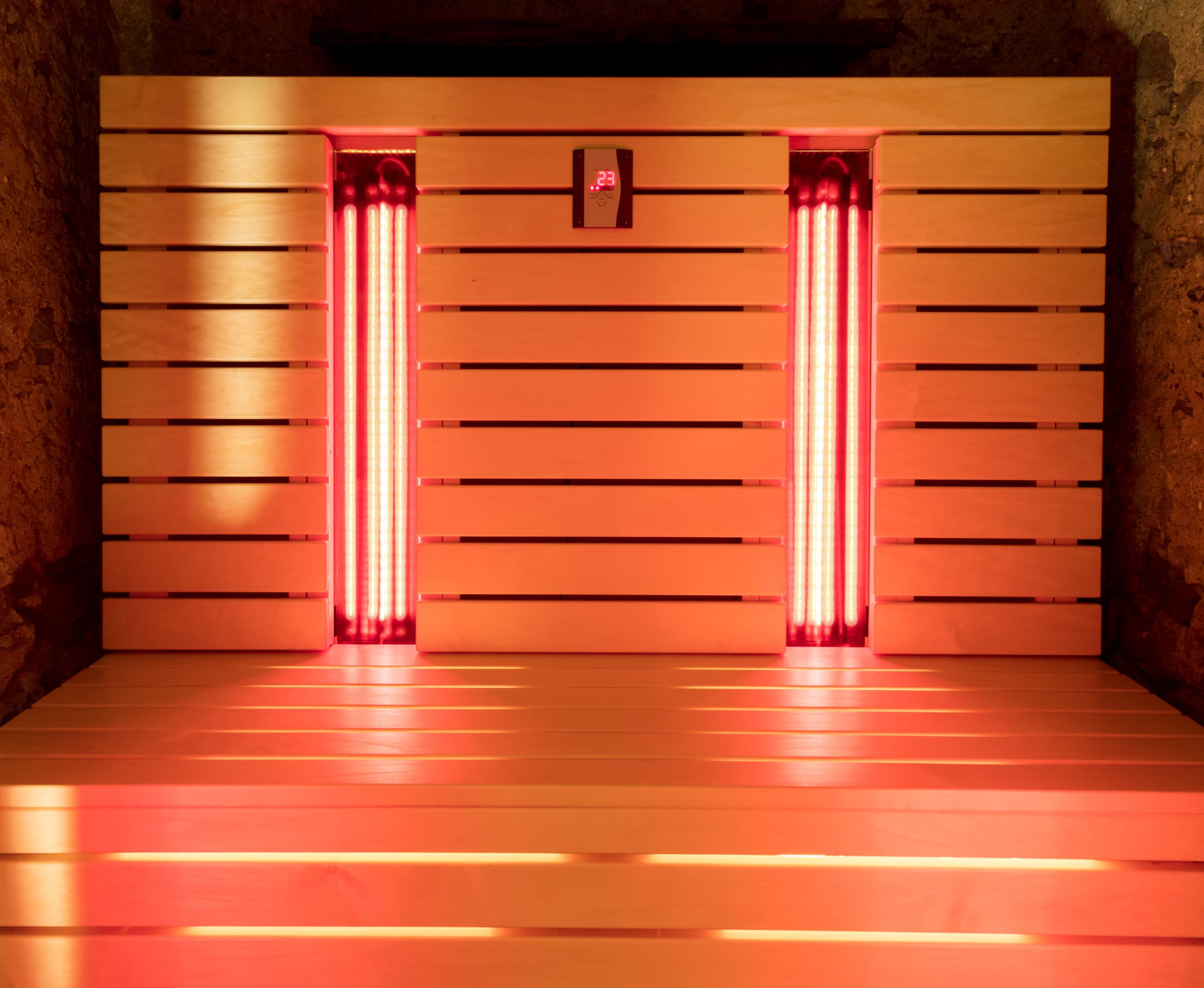 The infrared sauna Wooden infrared sauna interior with glowing red heaters and a digital temperature display showing 29°C.